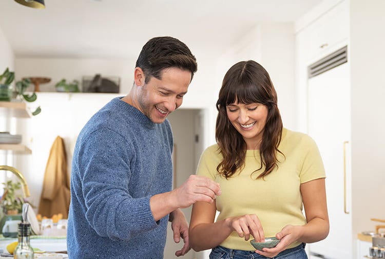 Smiling adult woman and smiling adult man cooking together at home