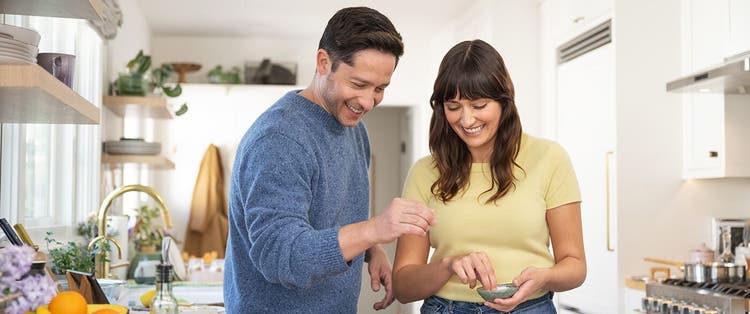 Smiling adult woman and smiling adult man cooking together at home