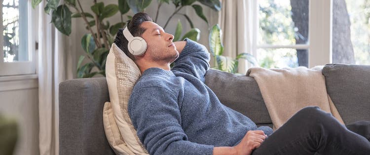 Man in casual clothing relaxing indoors on couch with headphones