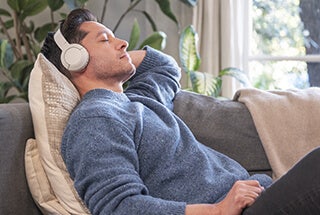 Man in casual clothing relaxing indoors on couch with headphones