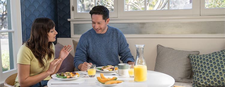 Adult man and woman seated at table and eating meal together at home