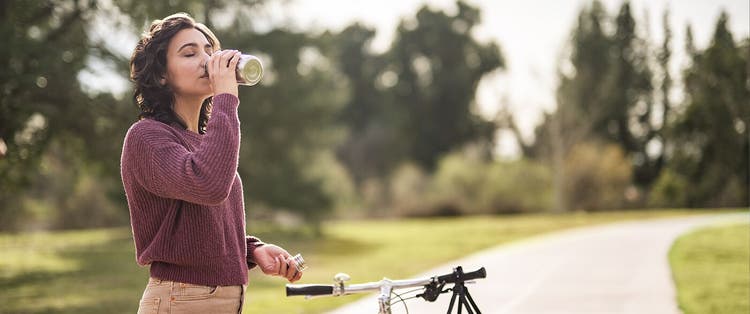 Adult woman standing on outdoor cycling path with bike