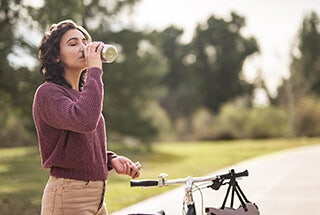 Adult woman standing on outdoor cycling path with bike